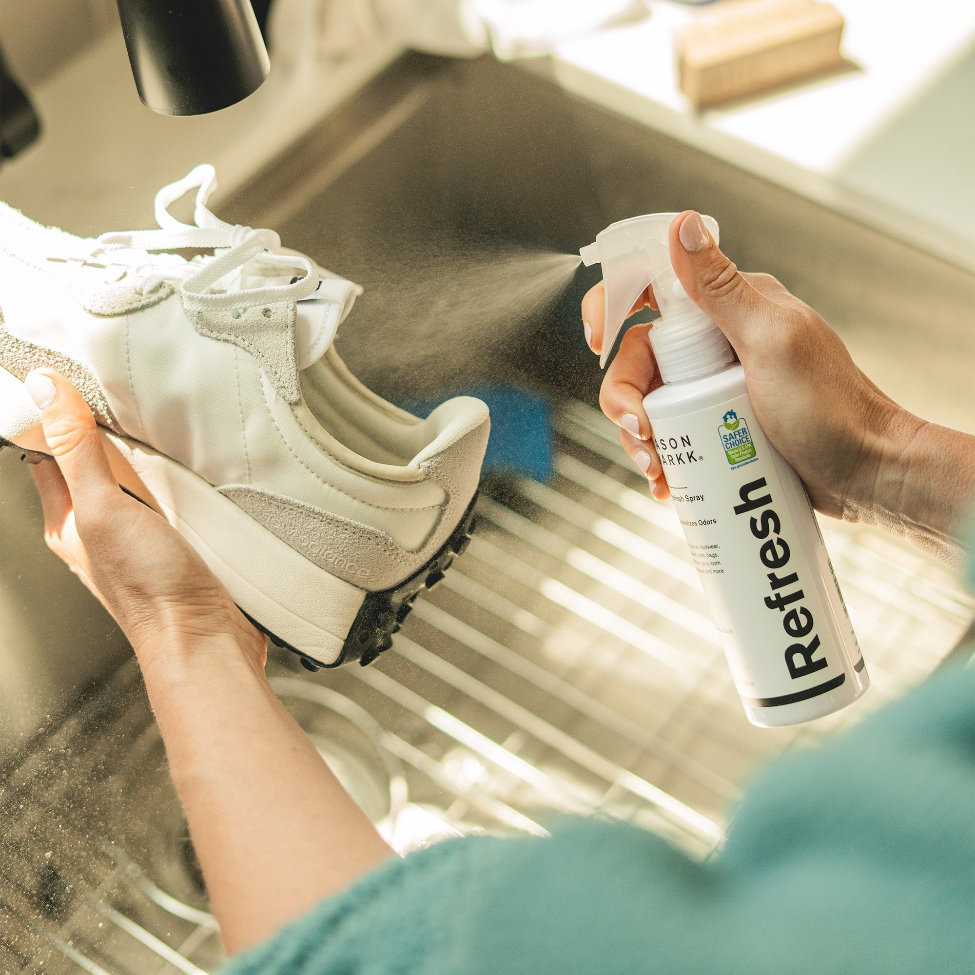 Person spraying a white pair of sneakers with Refresh