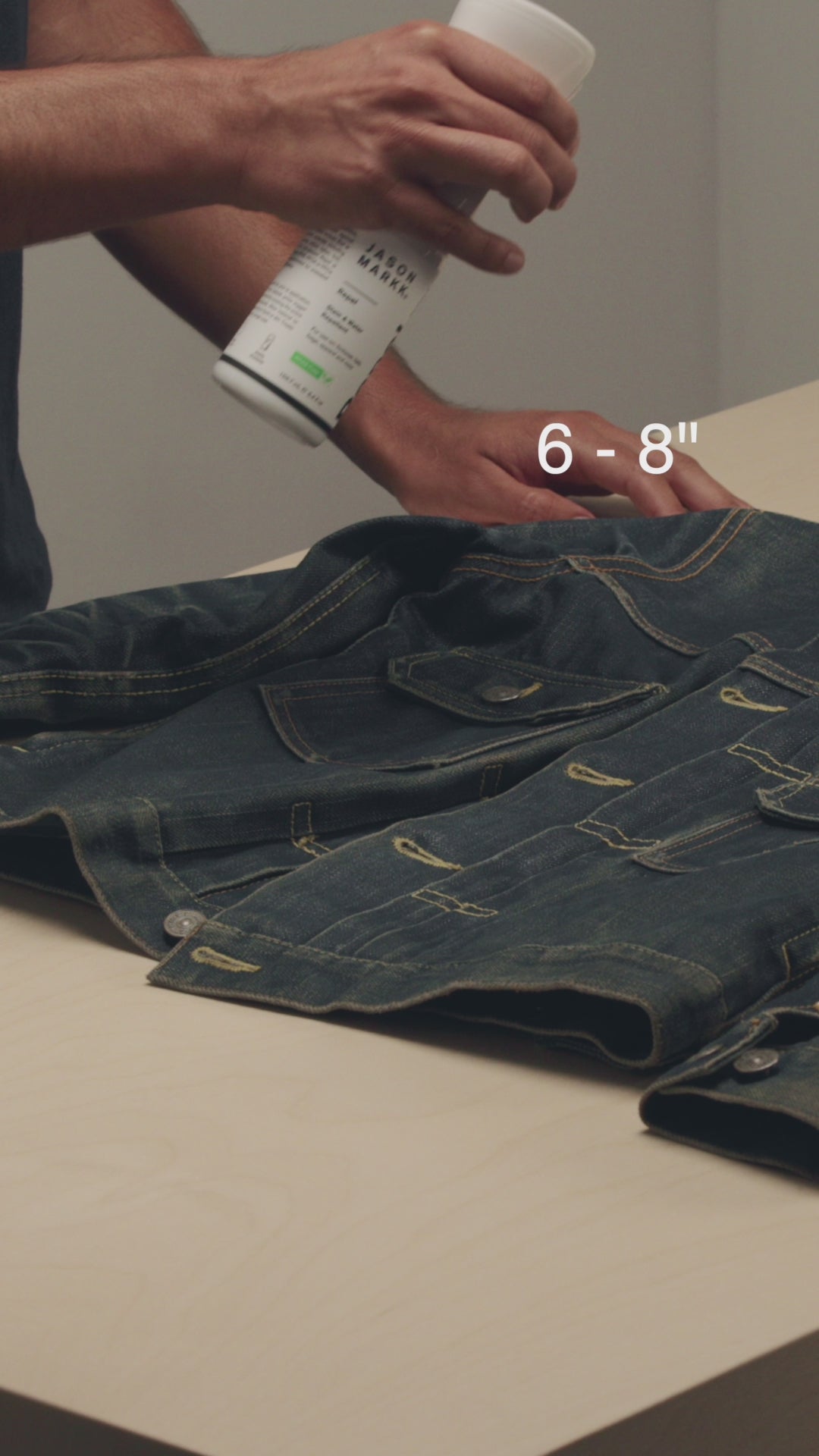 HOLDING A JASON MARKK REPEL SPRAY 6 TO 8 INCHES FROM A VISVIM DENIM JACKET
