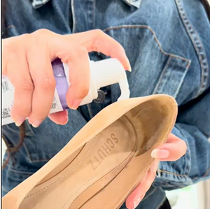 Person applying a RTU Foam to a beige shoe with a denim jacket in the background